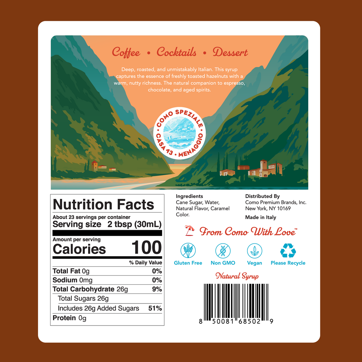 The back label, featuring a colorful mountain landscape illustration with a mountain goat and a white nutrition facts panel on a brown background. Nutrition Facts of the Como Speziale Hazelnut Syrup. 100calories per 2 tablespoons. 
