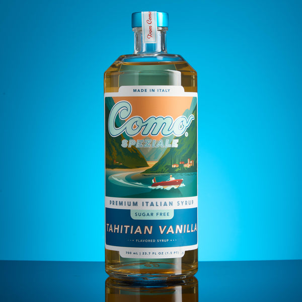 A bottle of Como Tahitian Vanilla premium Italian syrup, featuring a colorful label with a boat illustration, set against a vibrant blue gradient background.